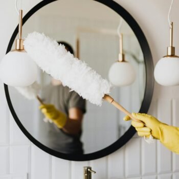 Crop woman dusting lamp during housework